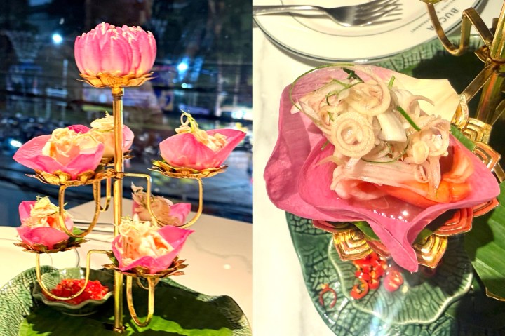 A beautifully arranged Lotus Flower Salad served in pink lotus petals, showcasing shrimp and herbs, with a gold stand and a contrasting green plate.