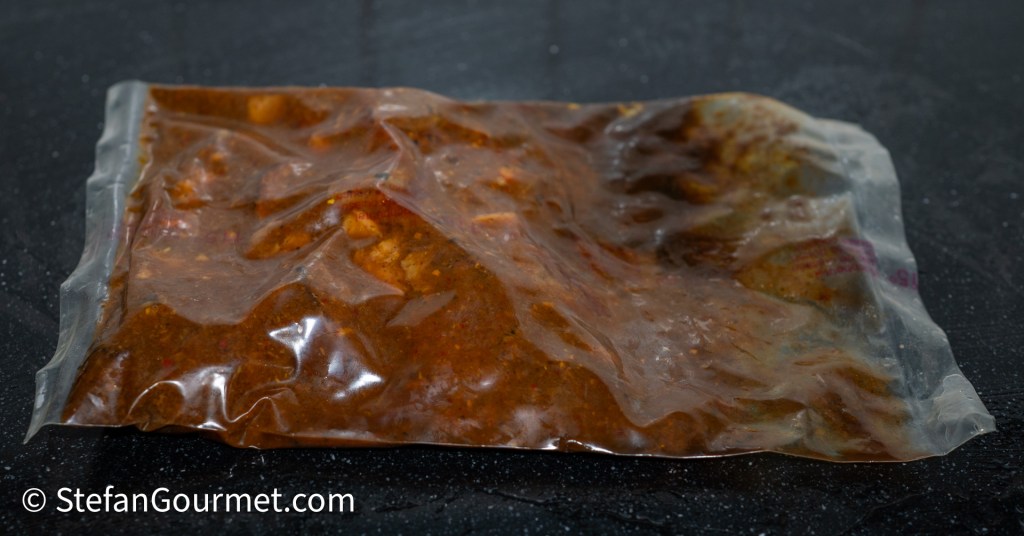 Vacuümverpakking met Gaeng Hung Lay curry, met de rijke bruine saus en stukjes gemarineerd vlees.