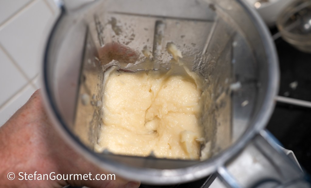 A close-up view of a blender containing a smooth, creamy parsley root puree, ready for serving.
