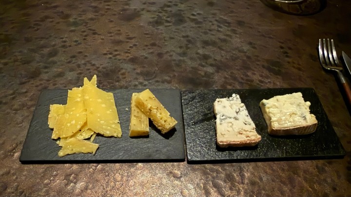 A selection of aged cheeses served on slate, including hard cheeses and blue cheese.