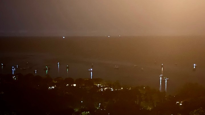 View of Koh Tao bay at night, featuring fishing boats illuminated with bright lights.