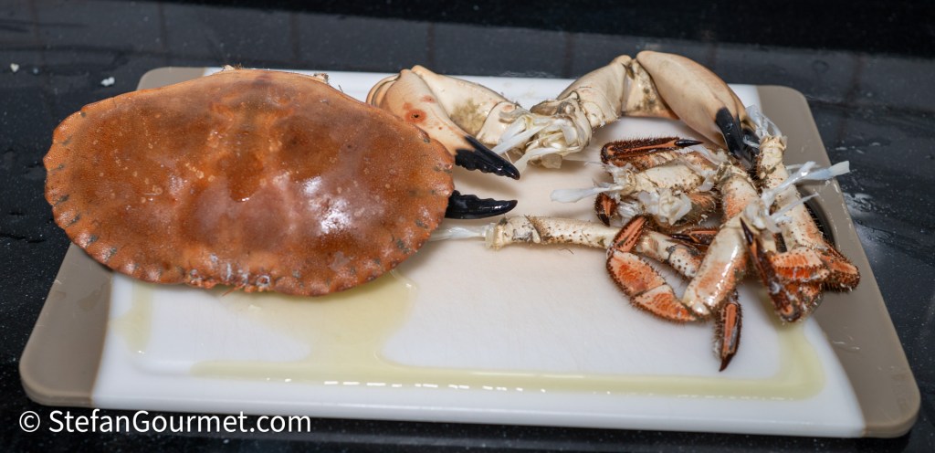 A whole crab displayed on a cutting board, showcasing its large shell and claws.