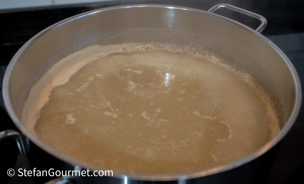 A pot of boiling liquid on a stovetop, with bubbles rising to the surface.