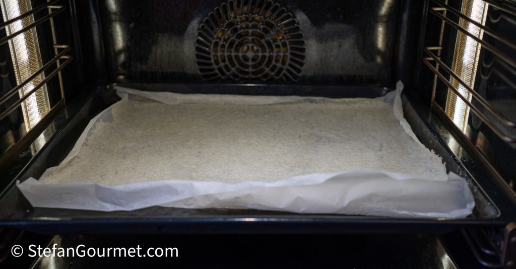 An empty baking tray lined with parchment paper inside an oven.