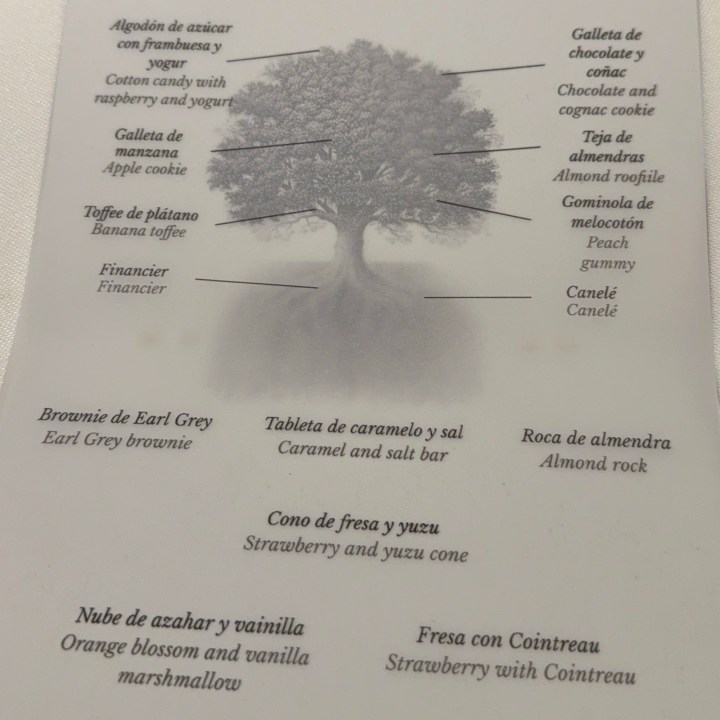 Menu featuring a tree illustration with various dessert items labeled, including cotton candy with raspberry and yogurt, apple cookie, banana toffee, financier, Earl Grey brownie, caramel and salt bar, strawberry and yuzu cone, orange blossom and vanilla marshmallow, chocolate and cognac cookie, almond roof tile, peach gummy, canelé, almond rock, and strawberry with Cointreau.
