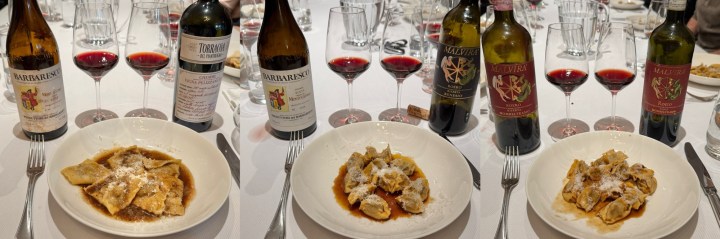 A dining table set with three plates of pasta dishes and several wine bottles, accompanied by glasses of red wine.