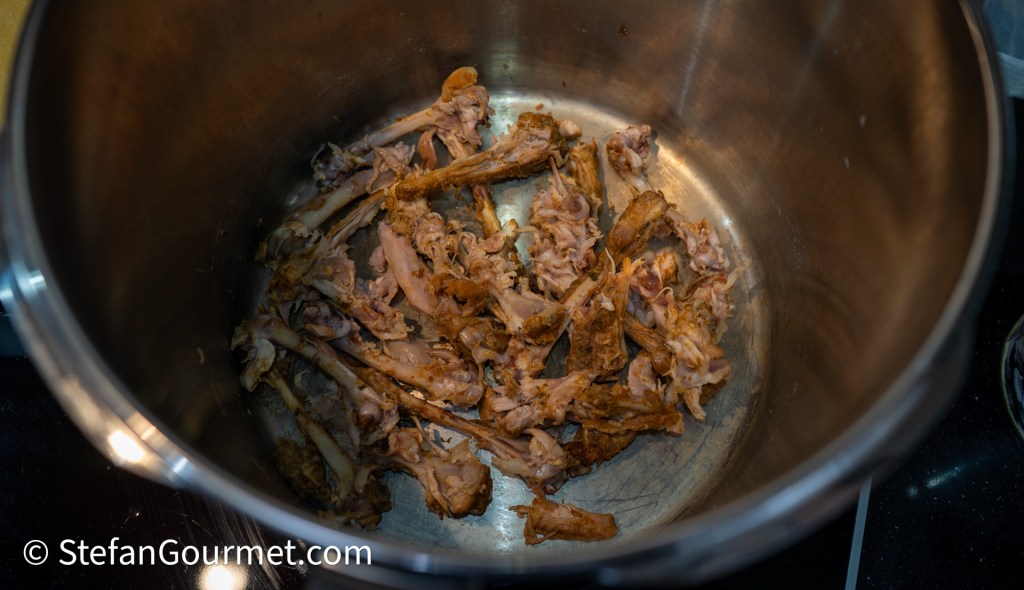 A pot containing leftover chicken bones after cooking.