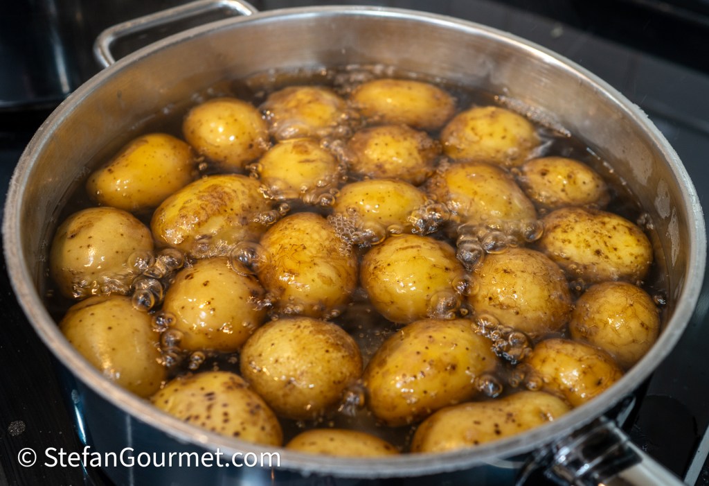 A pot filled with boiling potatoes, with some water bubbling around them.