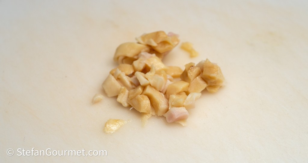 Chopped pieces of ginger on a cutting board.