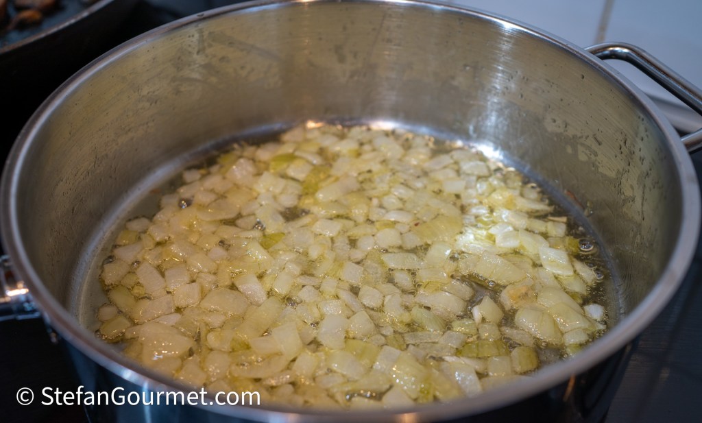 Chopped onions sautéing in a pot with oil.