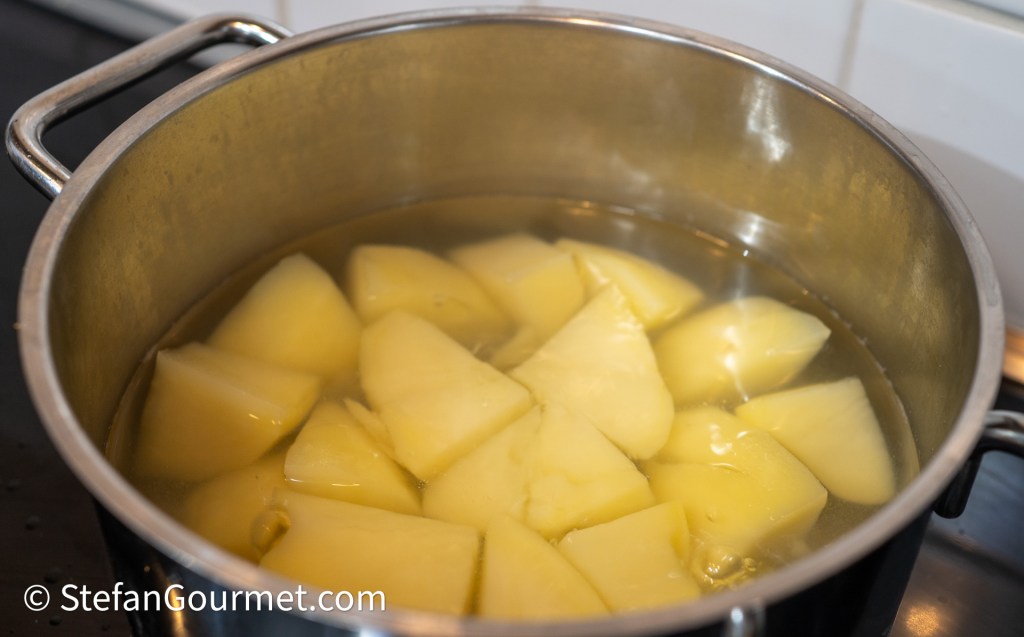 A pot of boiling water containing cut potatoes, ready for cooking.