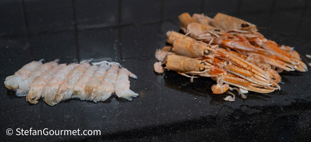 Close-up of two types of seafood on a dark surface: one side features peeled shrimp, while the other side displays whole langoustines.