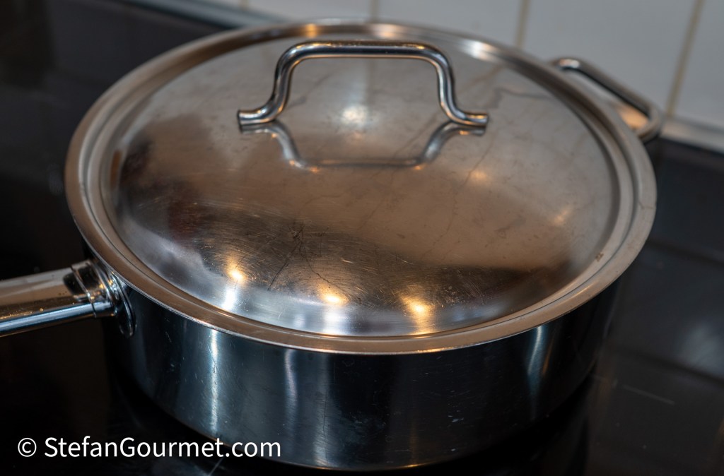 A stainless steel saucepan with a lid placed on a stovetop.