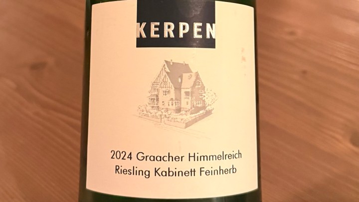 Close-up of a wine bottle label featuring the text 'KERPEN', the vintage year '2024', and the variety 'Graacher Himmelreich Riesling Kabinett Feinherb' with an illustration of a house.
