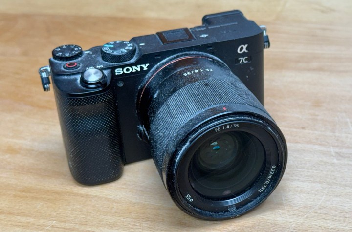 A close-up view of a Sony Alpha 7C camera with a lens mounted, resting on a wooden surface.
