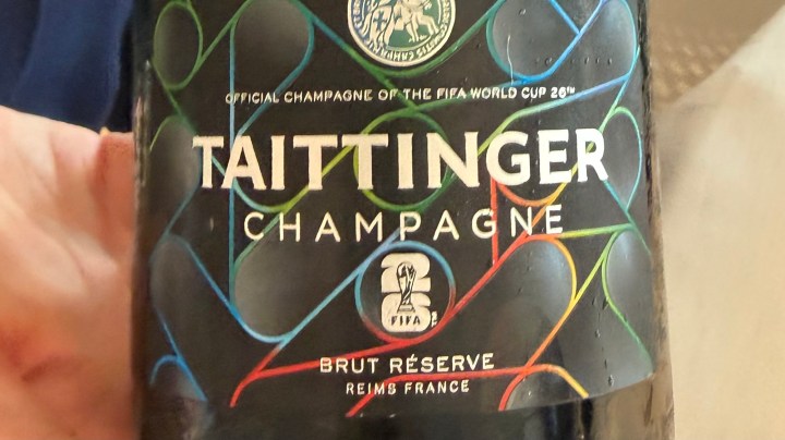 Close-up of a Taittinger Champagne bottle featuring the label that reads 'Official Champagne of the FIFA World Cup 2018', with vibrant geometric patterns in blue, green, and red.