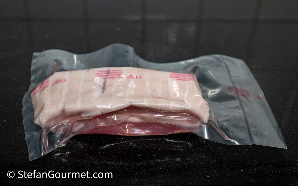 Vacuum-sealed package of sliced meat on a glossy black surface.