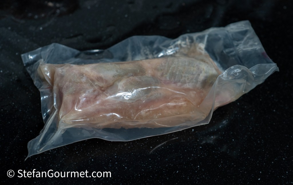 Vacuum-sealed piece of fish wrapped in transparent plastic.