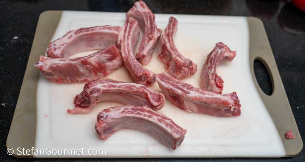 Raw pork ribs arranged on a cutting board.