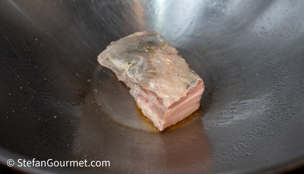 A piece of meat cooking in a frying pan, showing a glistening surface.