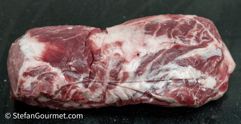 A piece of raw marbled meat on a black countertop.