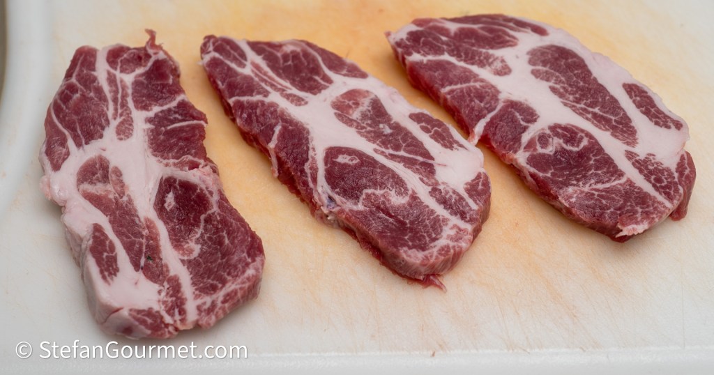 Three sliced pieces of pork meat arranged on a cutting board with visible marbling.