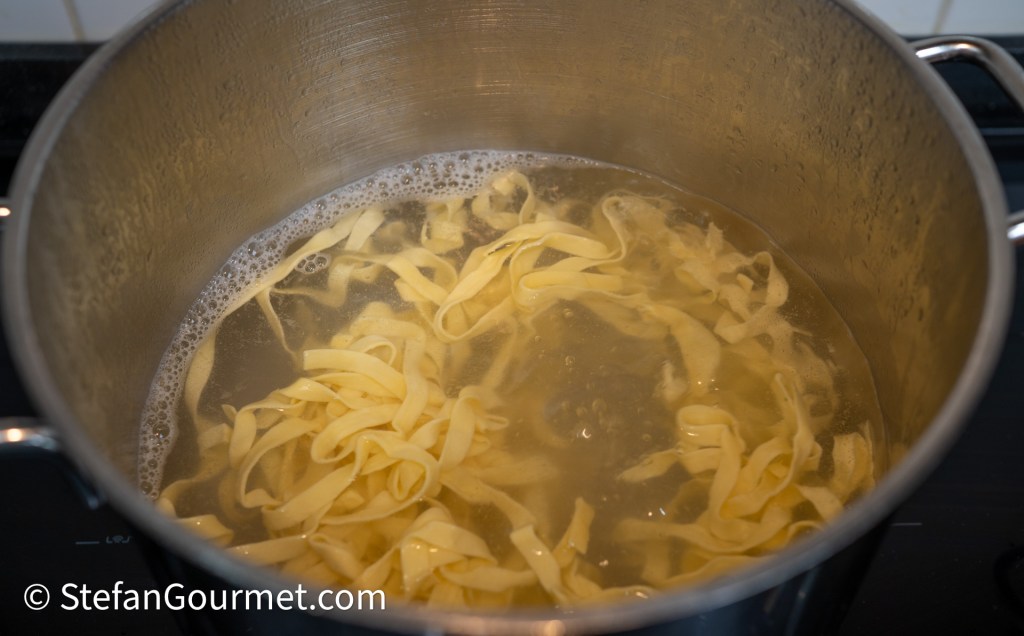 A pot of boiling water with fresh pasta cooking inside.
