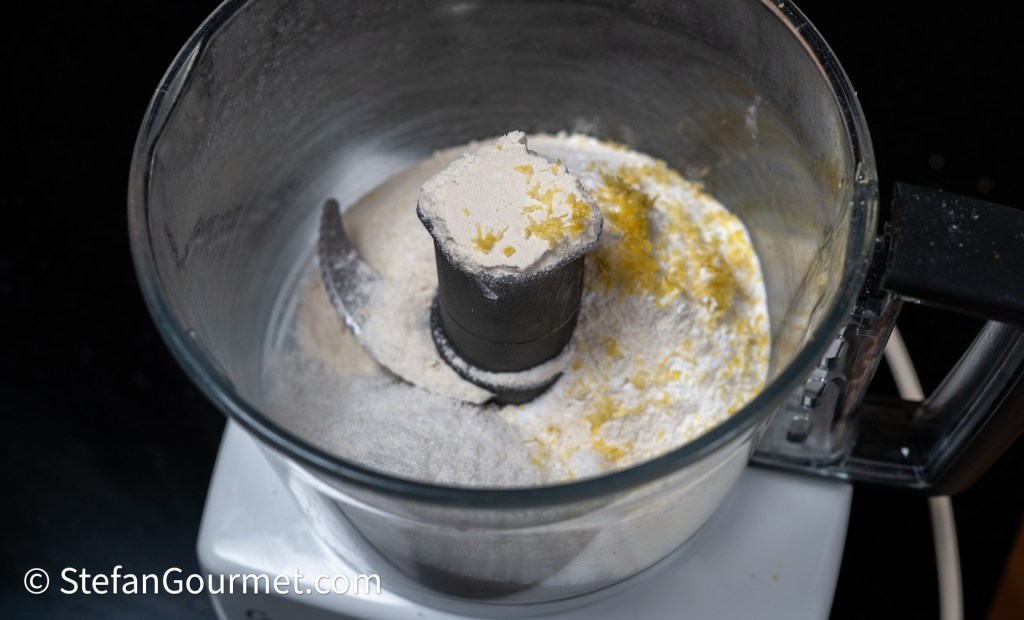 A food processor containing flour and zest, viewed from above.